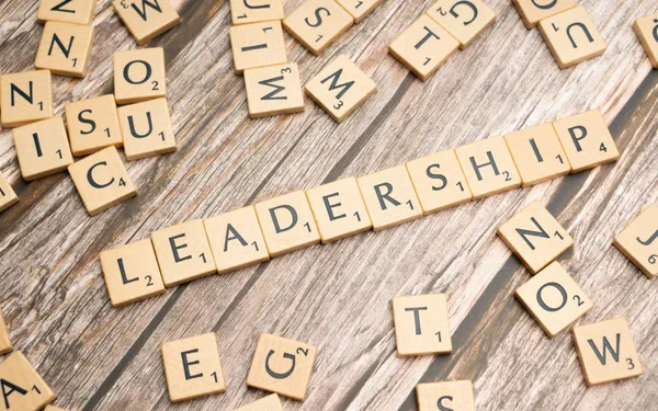 Wooden Scrabble tiles spelling out 'LEADERSHIP' on a rustic wood surface