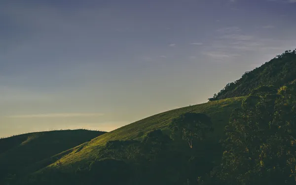 Sunlight falling across green rolling hills beneath an open sky